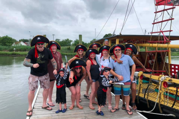 a group of people on a boat posing for the camera with a pirate hats